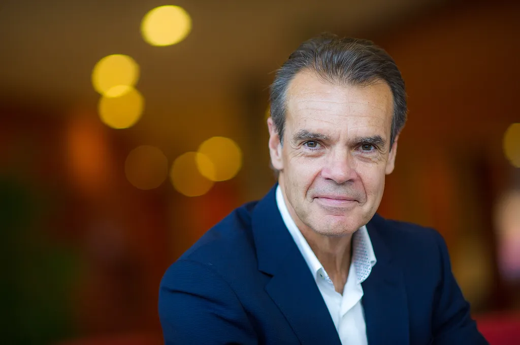 Retrato profesional de Prudenci Molas socio fundador de Atlantis con traje oscuro y expresión serena, situado en un entorno interior luminoso con desenfoque de luces cálidas al fondo.