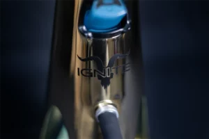 Detalle cercano del cuerpo dorado de una shisha Nebben mostrando el logotipo Ignite y la entrada de la manguera, destacando acabados metálicos y diseño preciso.