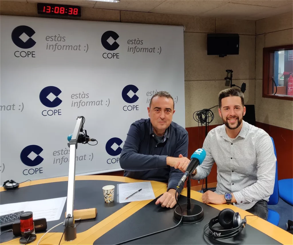 Dos profesionales en un estudio de radio durante una entrevista, sentados frente a micrófonos y equipo técnico, simbolizando la presencia mediática conseguida para Sensation Apartments.
